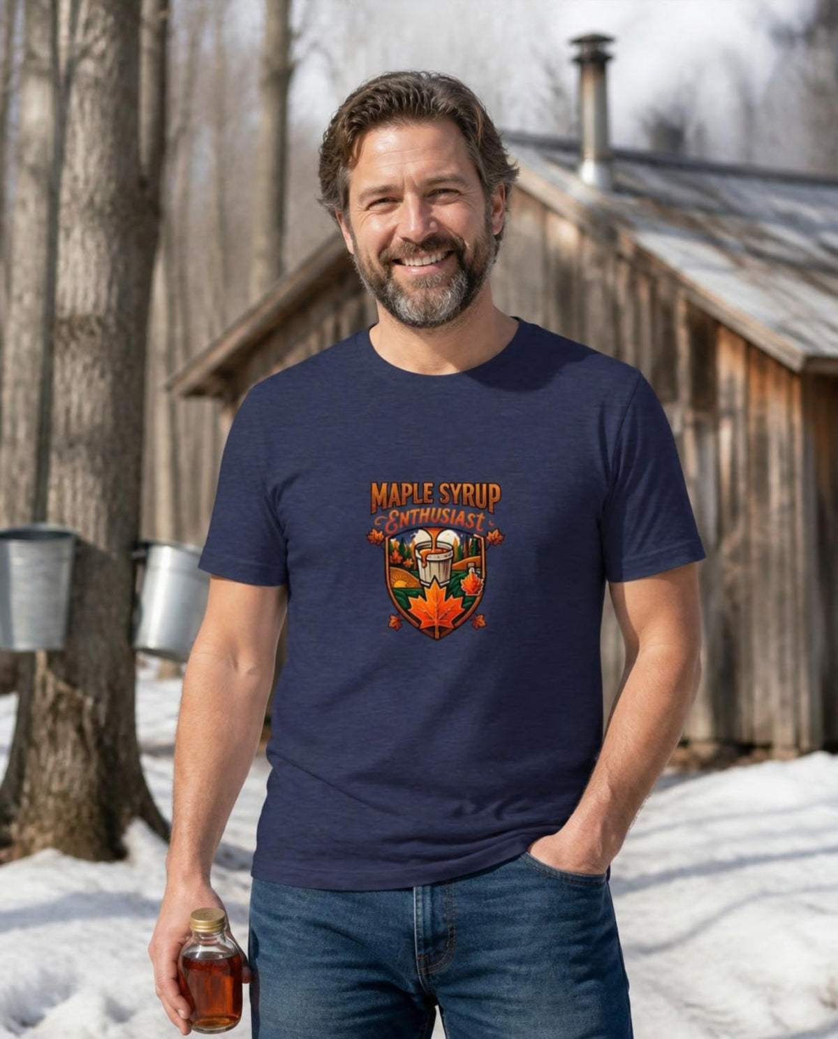 Man wearing a navy Maple Syrup Enthusiast t-shirt outside a sugar shack