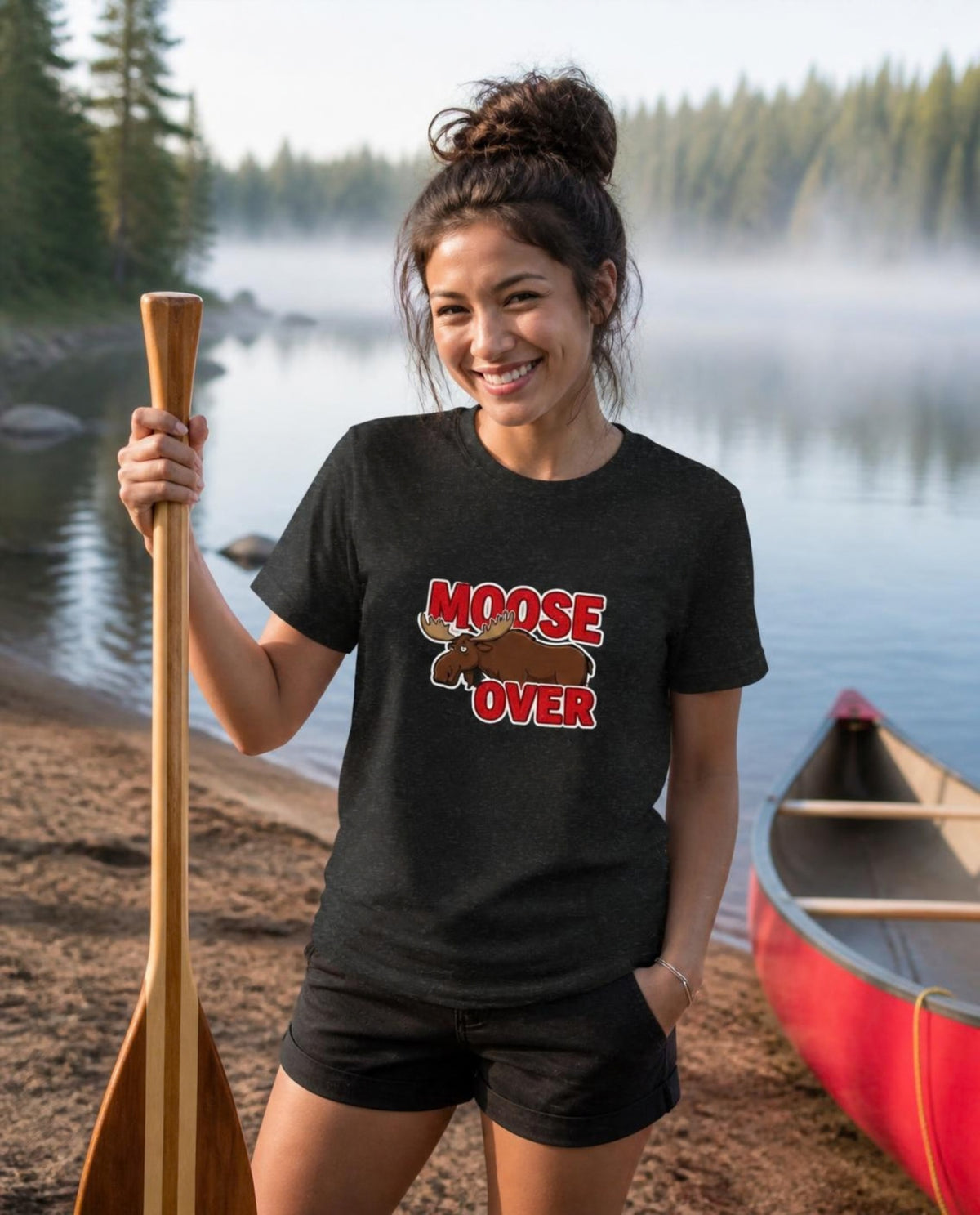 Woman wearing a black Moose Over t-shirt at a lakeside canoe launch